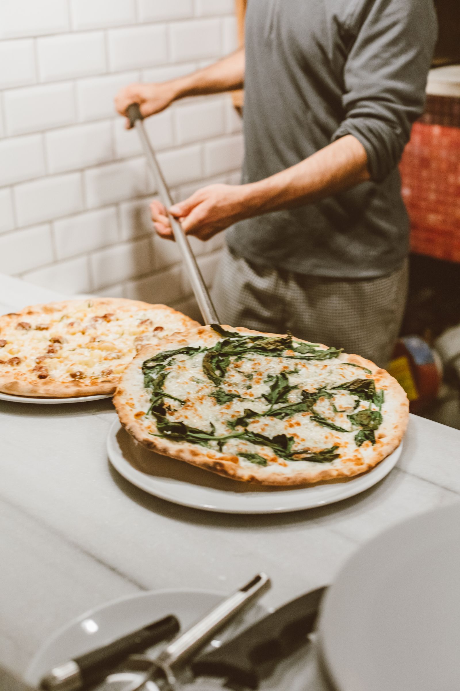 A pizza maker serving freshly cooked pizzas